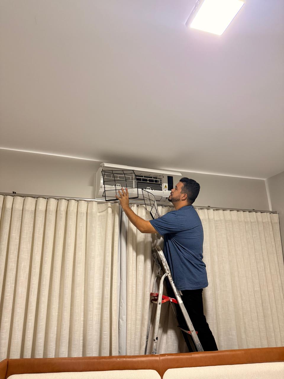 Técnico da Clima Pontes realizando limpeza do filtro de um split em ambiente residencial